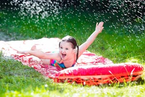 Kind rutscht auf Wasserrutsche Garten